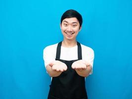 Man apron showing empty hand uo with happy smile blue background photo