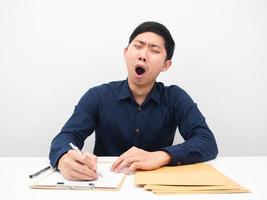 Asian man feeling sleepy and yawn lazy to working at his workplace on table photo