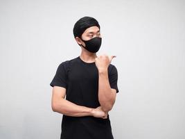 Portrait man wearing mask point finger and looking at right side on white background photo