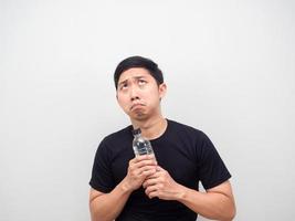 Asian man feeling afraid with water bottle in hand looking up copy space photo