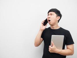 Man holding tablet with moblie phone feeling shocked looking at copy space photo