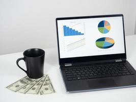 Laptop chart graph business with cofee cup and money dollar on the desk photo