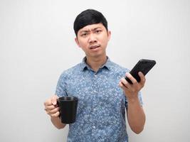 Man blue shirt talking with mobile phone and holding coffee cup feeling angry photo