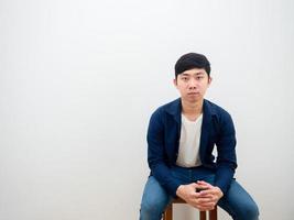 Asian man with jeans sitting on chair serious face looking at camera on white isolated background photo