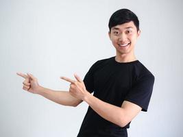 Cheerful asian man point double finger at left side on white wall background portrait photo