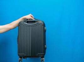 Man hand holding luggage on blue background photo