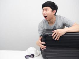 Asian man with luggage feeling amazed looking at copy space excited with holiday photo