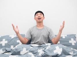 Asian man sitting on the bed feeling amazed and looking up photo