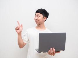 Asian man cheerful holding laptop point finger at space white background photo