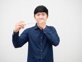 Asian man feeling shocked about thermometer in his hand close hid face by hand serious face photo