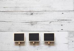 Three small clip chalkboard wood frame array line on white wood table top view nature shadow above space,Idea signboard concept photo