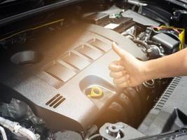 pulgar de la mano hacia arriba con el motor de un coche nuevo con destellos de luz foto