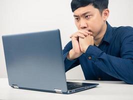 Man sitting at table looking at laptop serious emotion,Male employee photo