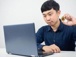 Man sit and looking at laptop show bitcoin in hand photo