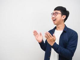 Asian man wearing glasses feeling happy and smile looking at copy space and show hand up photo