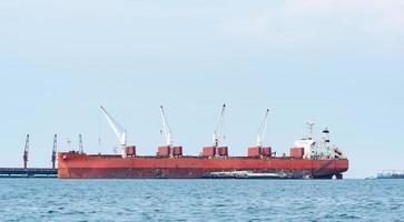 Large ship red color with big crane in the blue ocean and blue sky landscape,Industrial boat in the sea logistic concept photo