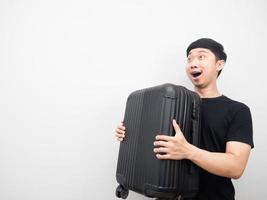 Cheerful man holding luggage feeling excited looking at copy space photo