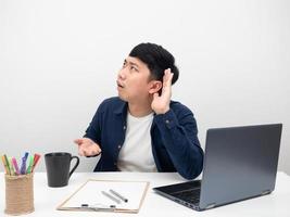 empleado masculino hombre sentado en el lugar de trabajo de la oficina gesto no puedo escuchar quiero más fuerte foto