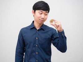 hombre asiático mirando bitcoin de oro en su nad con cara de sonrisa feliz sobre fondo blanco foto