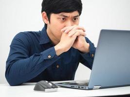 hombre trabajando desde casa y mirando la computadora portátil en la mesa sintiéndose serio sobre el trabajo foto