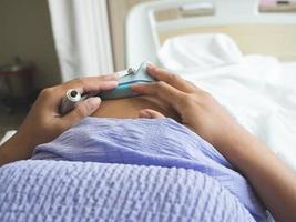mujer embarazada acostada en la cama revisando al bebé por equipo en el hospital