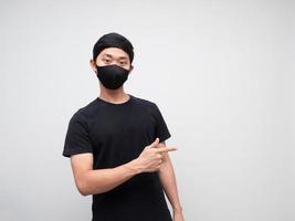 Portrait man wearing mask point finger right side and looking at camera on white background photo