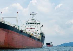 Big logistic ship unloading in the ocean with view mountain on island background and cloudy on sky,Shipping boat economy transportation concept on the sea photo