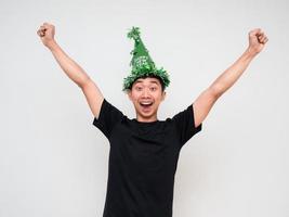 Young man happy and cheerful look at camera show arm and fist up with green hat and tassel colorful on white isolated happy new year concept celebration photo