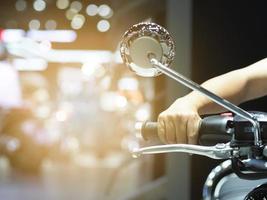 Man hand at handle motorcycle blur background,Hand catch handle bar of motorcycle with light flare photo