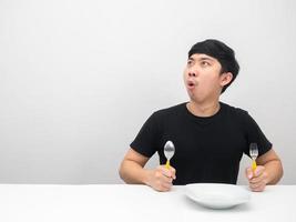 Man holding cutlery sit at the table feeling excited and looking at copy space photo