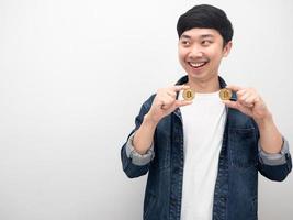 camisa de jeans de hombre asiático mantener bitcoin en la mano sonreír y mirar el espacio de copia foto