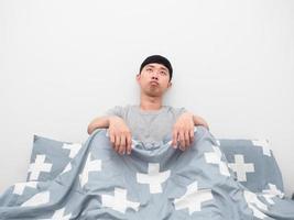 Asian man sitting on the bed bored emotion looking at copy space photo