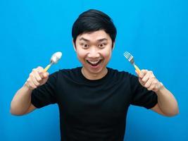 Man holding cutlery gesture eatting food and looking down blue background photo