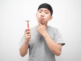 hombre asiático sosteniendo el afeitado y mirando su barbilla retrato fondo blanco foto