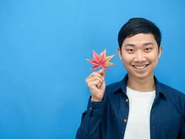 hombre asiático alegre sonrisa sosteniendo maple leaf head shot copia espacio fondo azul foto