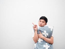 Asian man hugging pillow bored face point finger left side copy space white background photo