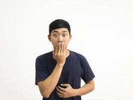 Portrait young man close right hand at mouth feel shock looking at camera big eyes in white isolated background crop half body photo