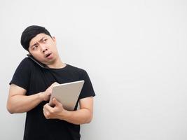 Man holding tablet and talking with mobile phone looking at copy space serious emotion photo