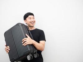 el hombre lleva equipaje sonriendo y mirando el espacio de la copia foto