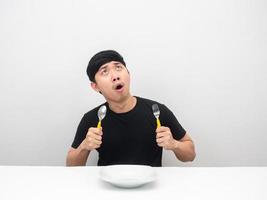 Man holding cutlery feeling hungry and looking up at copy space amazed emotion photo