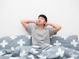 Asian man sitting on the bed gesture relax and thinking about something photo