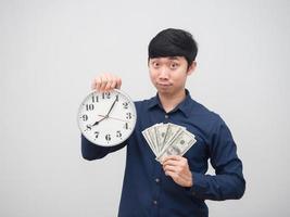 hombre asiático sosteniendo dinero y reloj en la mano mira el fondo blanco del retrato de la cámara foto