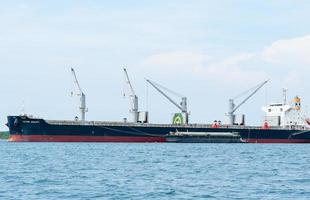 grúa en el barco industrial en el agua azul del océano y el paisaje del cielo azul, logística y concepto de barco de transporte en el mar foto