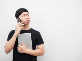 Man holding tablet and talking with mobile phone looking at copy space serious emotion photo