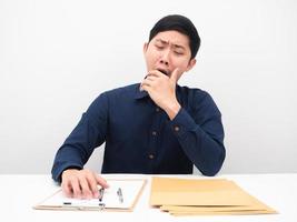 Asian man feeling sleepy and yawn lazy to working at his workplace on table photo