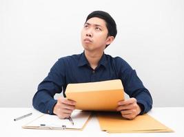 hombre sosteniendo un sobre de documentos y pensando en algo en su lugar de trabajo foto