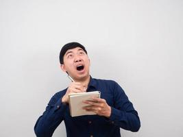 Man holding pen and diary feeling amazed looking up at copy space photo