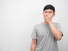 Asian man gesture close his nose feeling smelly looking at copy space photo