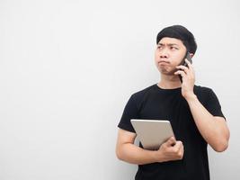 Man holding tablet and talking with mobile phone looking at copy space serious emotion photo