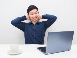 Asian man feeling relax and looking at laptop on the table workplace in the room white background photo